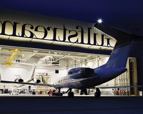 Exterior of Gulf Stream Service Center at night. Plane entering hangar.